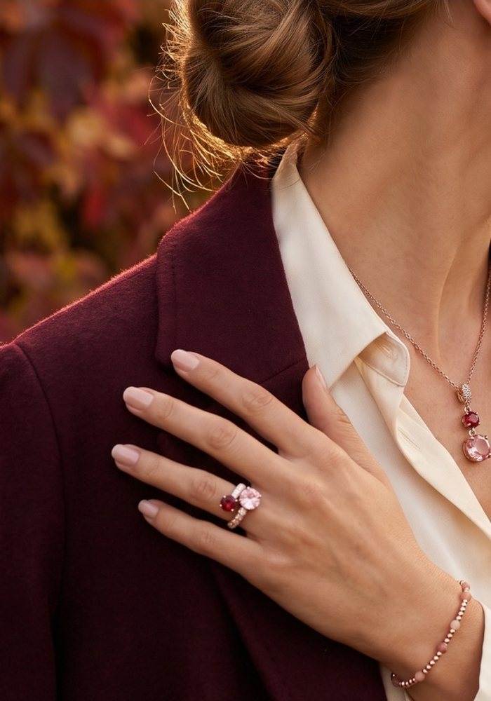Collana con pietre rosa e rosso e anello al dito, su cappotto bordeaux