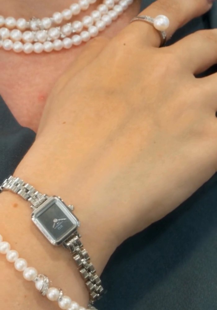 Bracciale di perle e orologio quadrato al polso