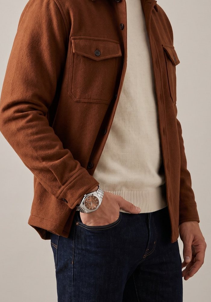Uomo con orologio automatico, overshirt ruggine e jeans